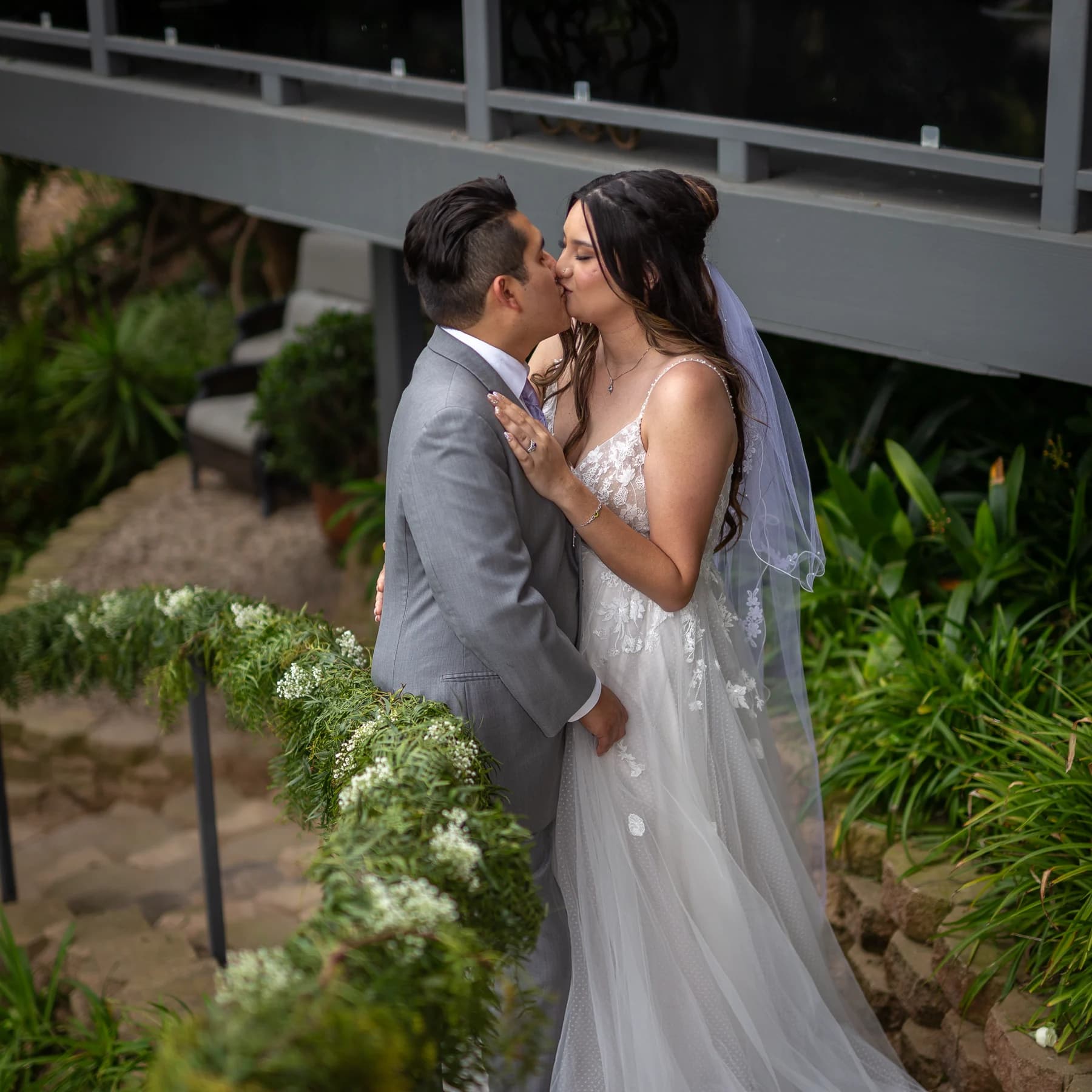 Newlyweds share a kiss in the garden at their Del Mar wedding