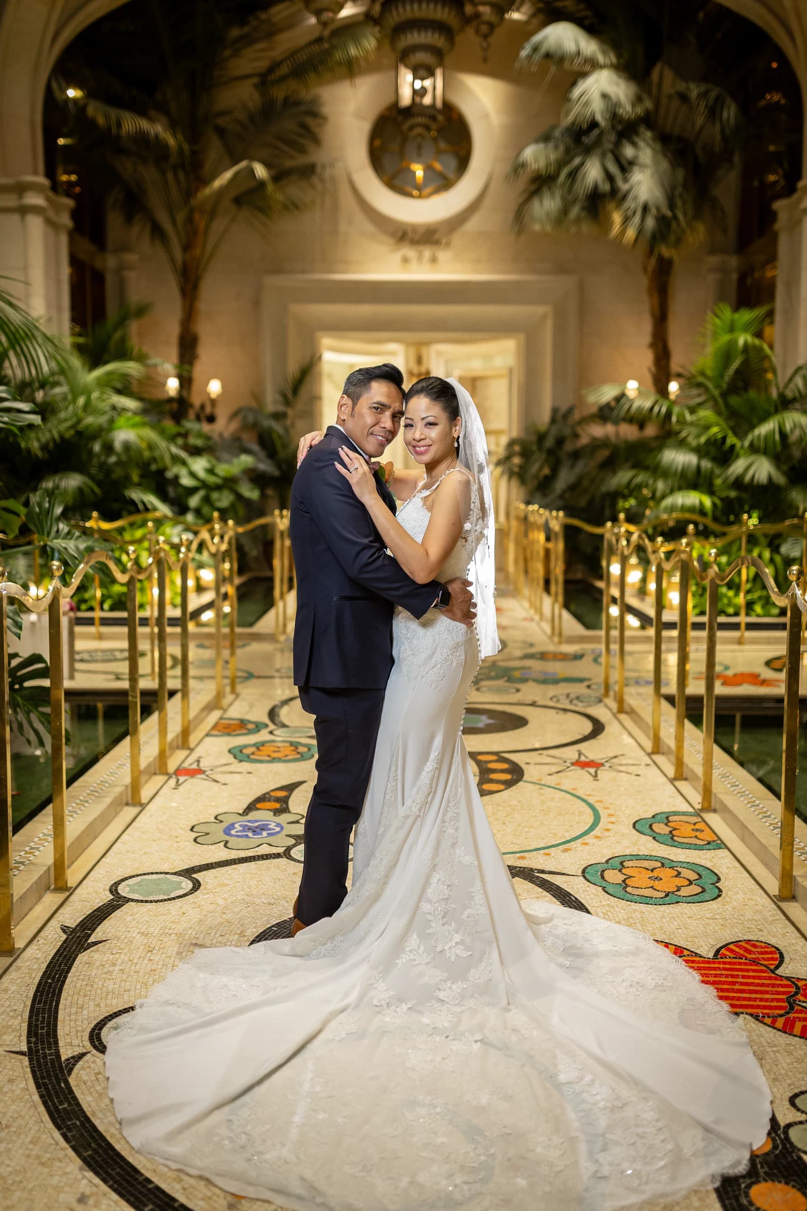 Newlyweds embrace in an ornate hotel corridor